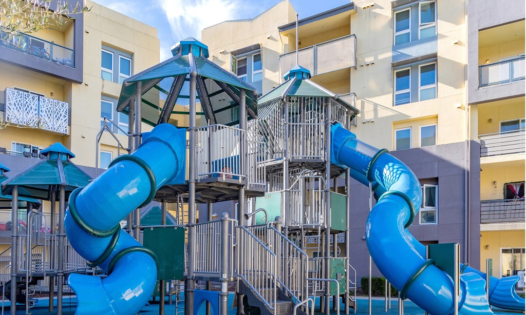 a playground with a blue spiraled slide in front of a building