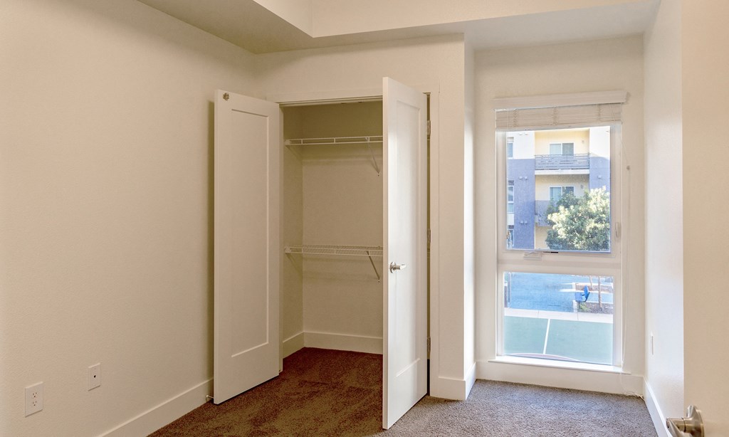 an empty bedroom with a closet and a window