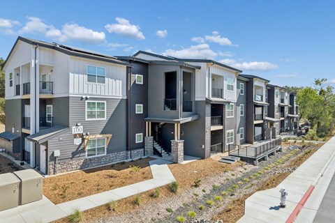 A modern apartment complex with balconies and a fire hydrant on the sidewalk.