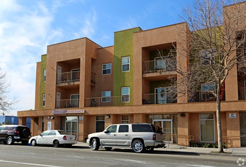 A multi-story apartment building with cars parked in front.
