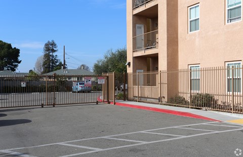 A parking lot in front of a tan apartment building.