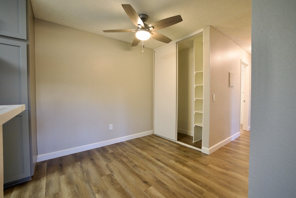 an empty living room with a ceiling fan and a closet at Brookhollow Apartments, West Covina , California