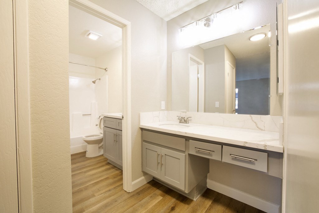 a bathroom with a large mirror and a sink and a toilet at Brookhollow Apartments, West Covina , California