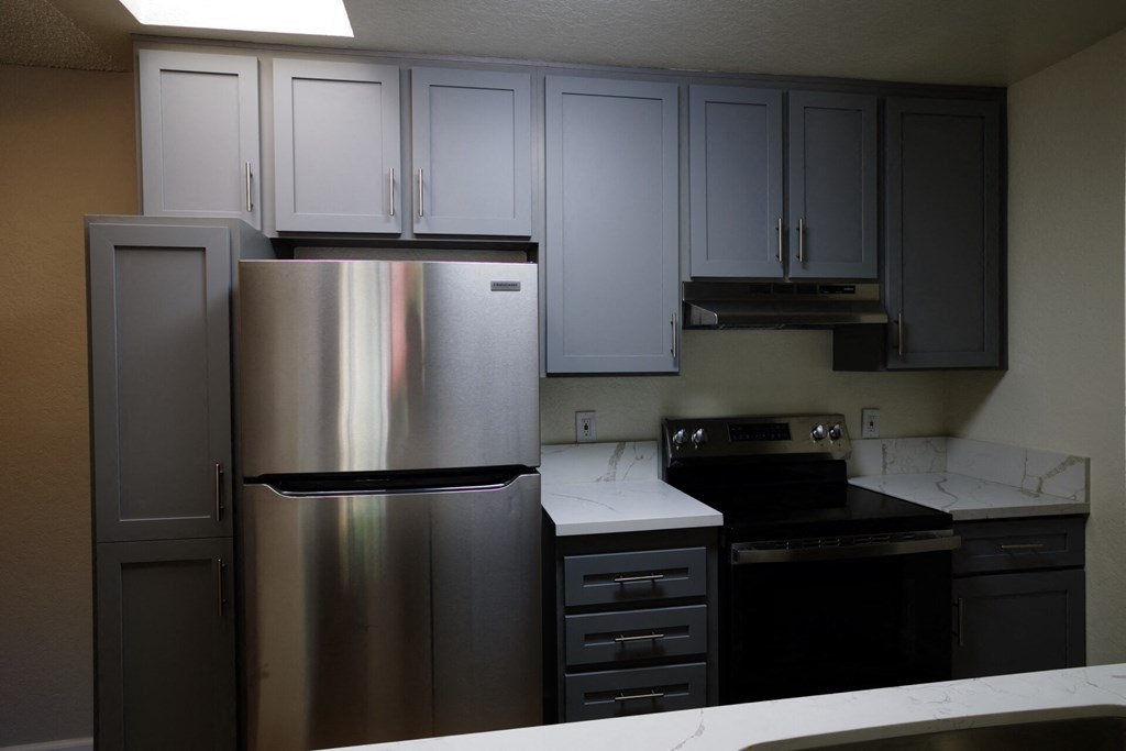 a kitchen with stainless steel appliances and white counter tops at Brookhollow Apartments, West Covina , California