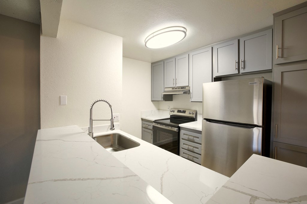 a kitchen with white marble counter tops and stainless steel appliances at Brookhollow Apartments, West Covina , California