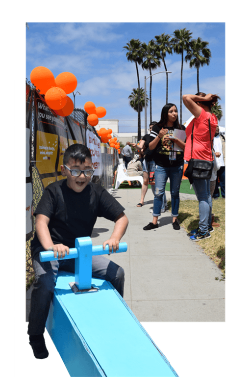 a young boy riding a blue scooter on a sidewalk with balloons