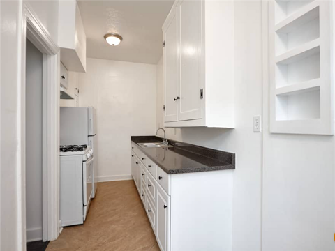 a kitchen with white cabinets and a black counter top