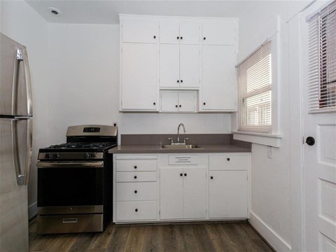 a kitchen with white cabinets and a stove and a sink