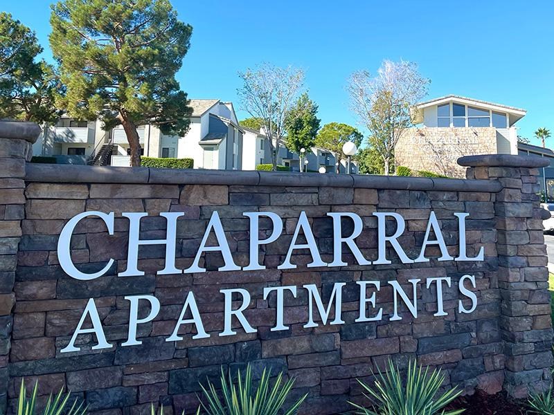A sign that says Chaparral Apartments in front of some houses.