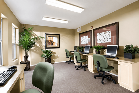 A room with a desk, chairs, and computers.
