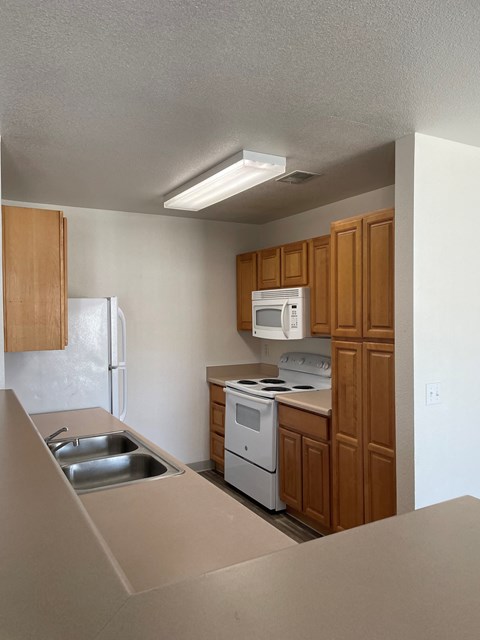 an empty kitchen with white appliances and wooden cabinets