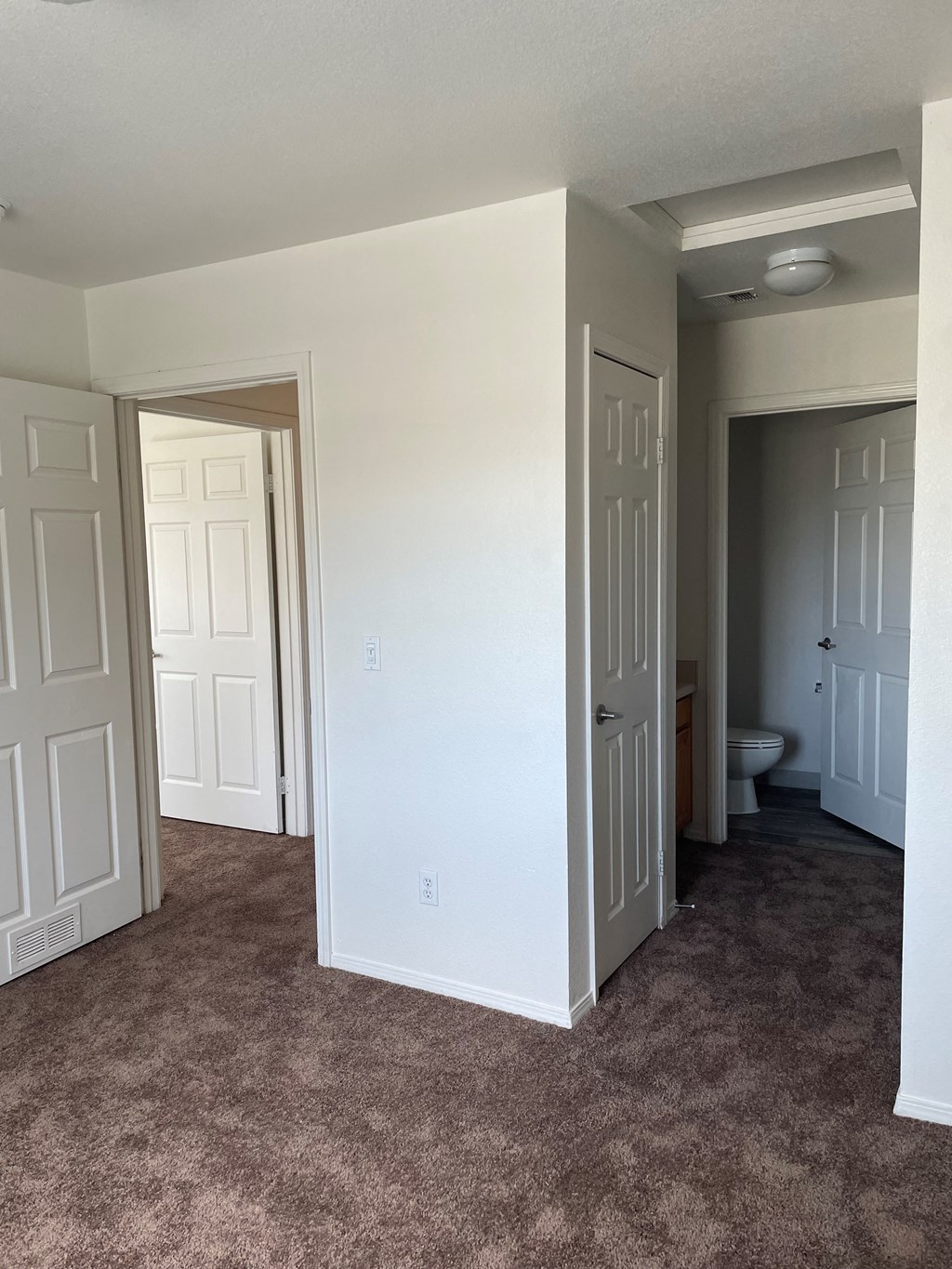 an empty room with a carpeted floor and a toilet in the distance