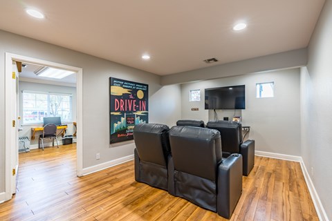 A living room with a poster on the wall and a row of black leather chairs.