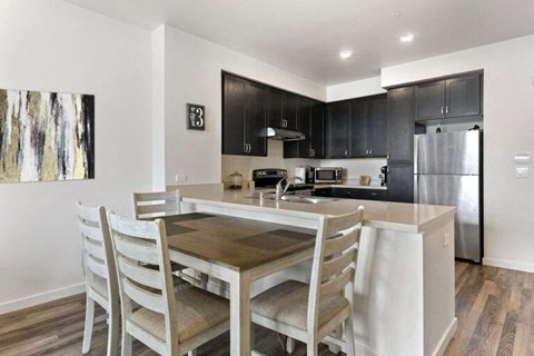 A kitchen with a table and chairs in front of a refrigerator.