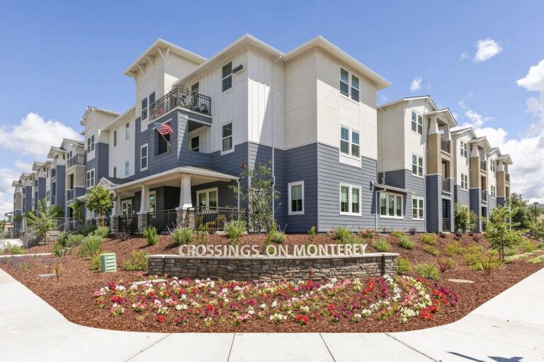 a crossroads on montgomery apartment building with a flower garden in front of it