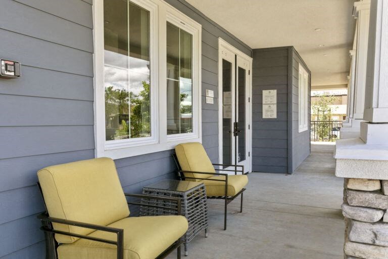 the front porch of a house with two chairs and a table
