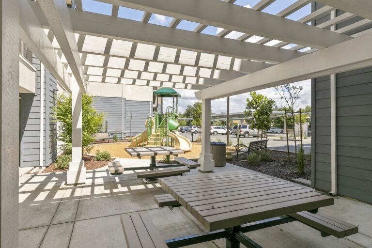 an outdoor patio with picnic tables and a playground
