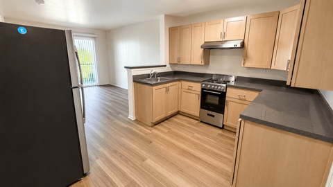 A kitchen with wooden cabinets and a black fridge.