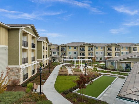 an exterior view of an apartment complex with a green courtyard
