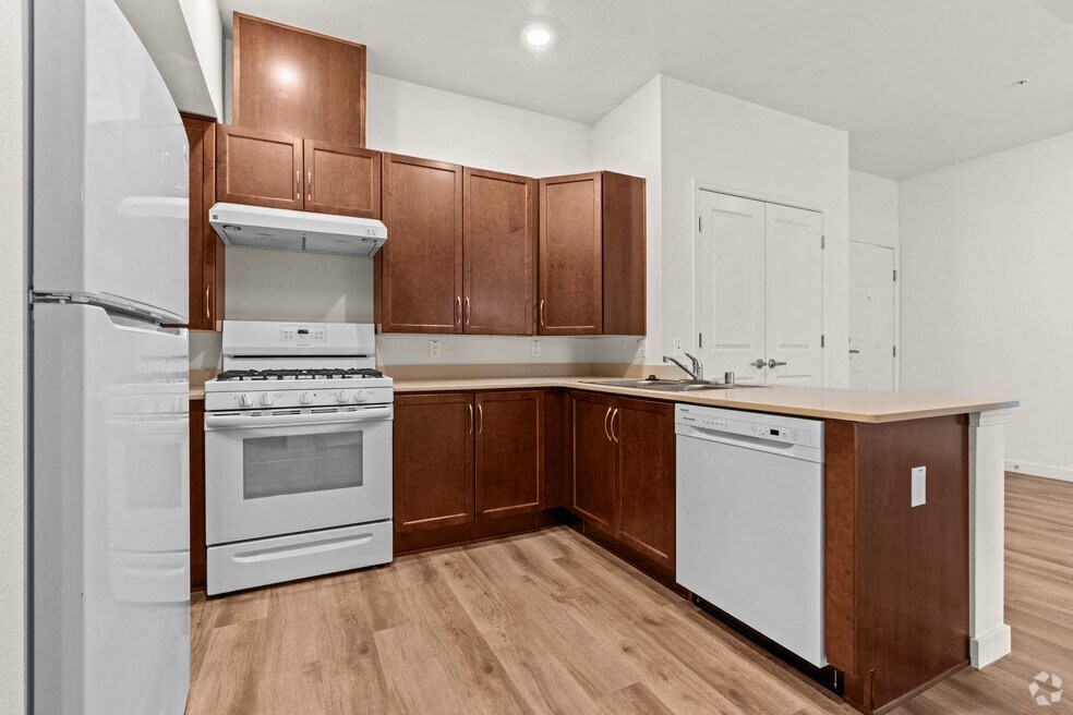 another view of a kitchen with white appliances and wooden cabinets