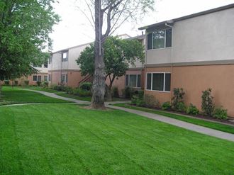 an apartment building with a green lawn and sidewalk