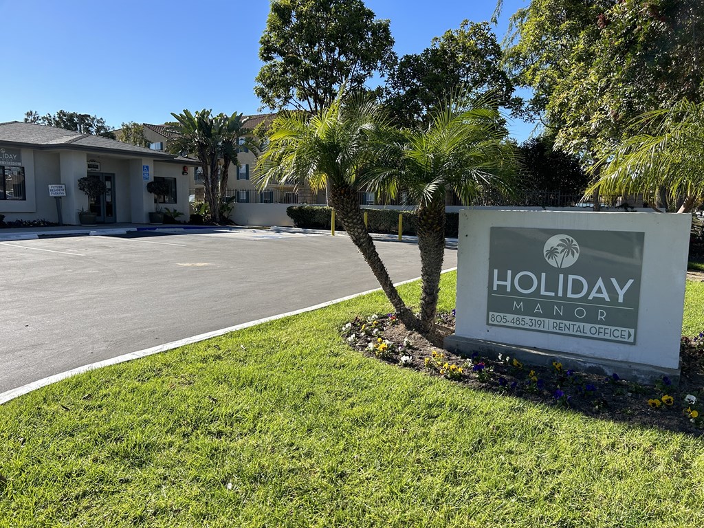 a sign that says holiday manor in front of a palm tree