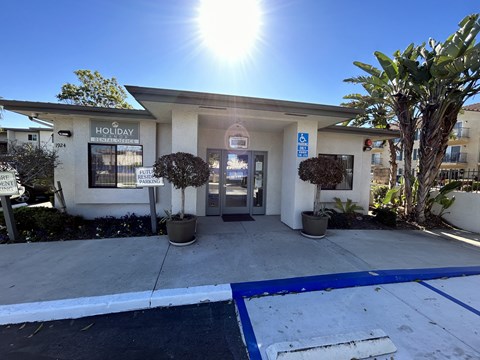 the front entrance of a building with a driveway and palm trees