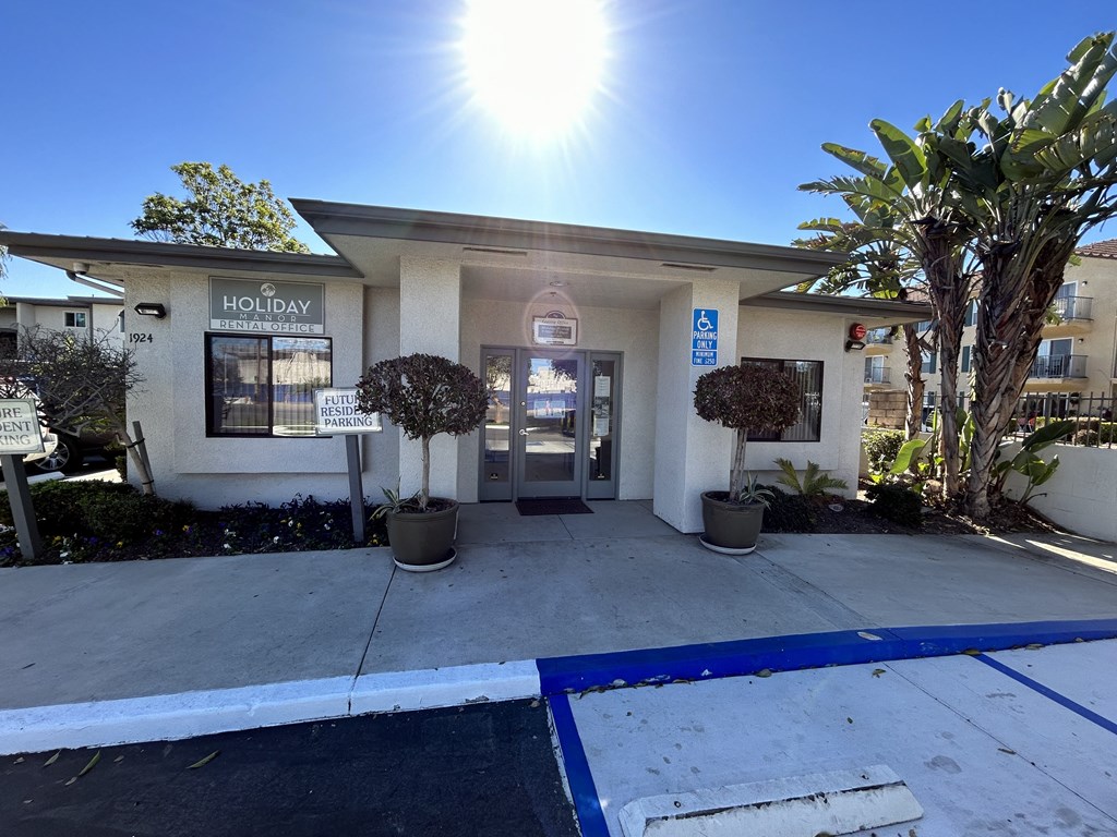the front entrance of a building with a driveway and palm trees