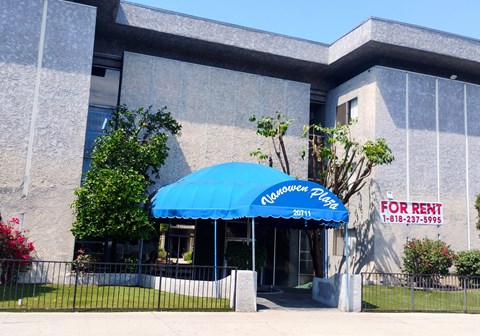 A building with a blue umbrella and a for rent sign.