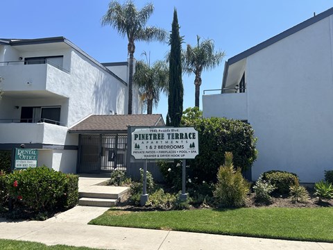 a building with a sign in front of it with palm trees
