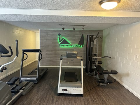 a gym with weights and a treadmill in the corner of a room