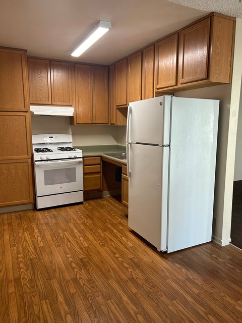 a kitchen with a refrigerator and stove and wooden cabinets