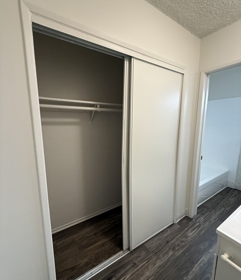 A white closet with a sliding door is open.