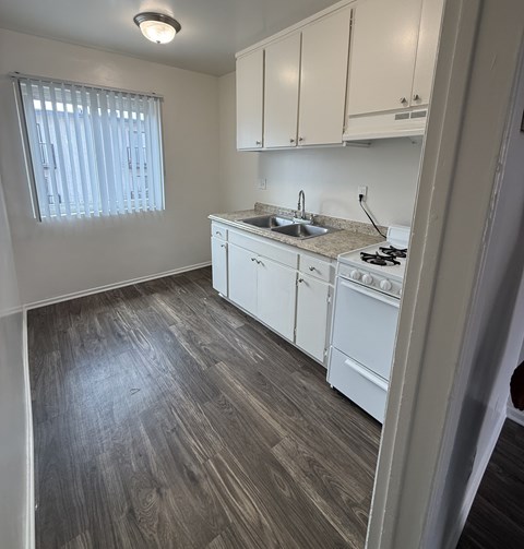 A kitchen with white cabinets and a wooden floor.