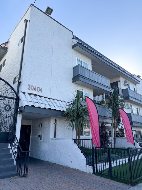 A white building with a black gate and a red banner.