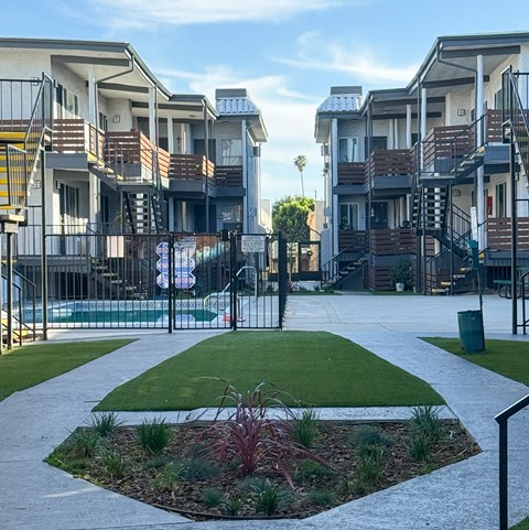 A residential area with apartment buildings and a small garden in the foreground.