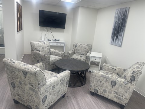A living room with a TV and chairs.
