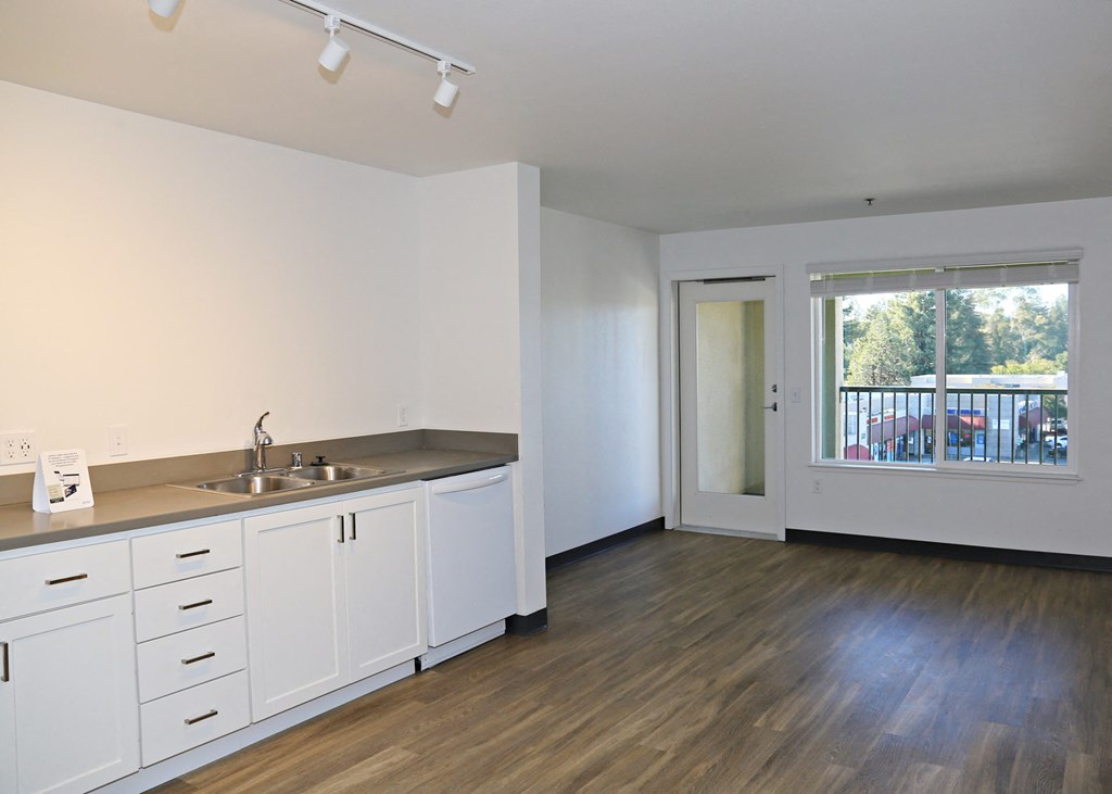 A kitchen with white cabinets and hardwood floor.