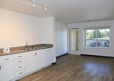 A kitchen with white cabinets and a wooden floor.