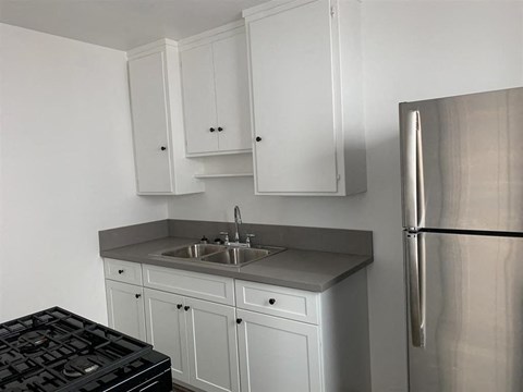 a kitchen with white cabinets and a stainless steel refrigerator