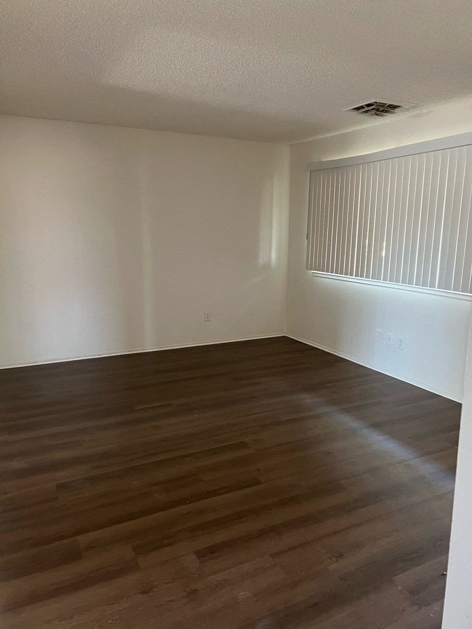 an empty living room with wooden floors and a window