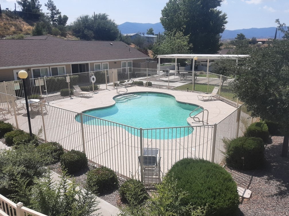 a pool with a fence around it and a house in the background