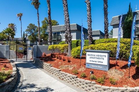 The image shows the entrance to Marina Heights Apartments with a sign and a gate.