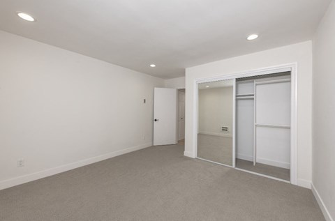a bedroom with a closet and a mirrored closet door