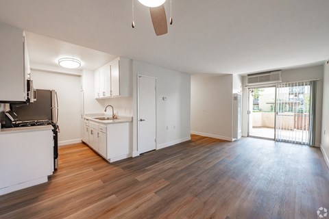 A kitchen with white cabinets and a wooden floor.