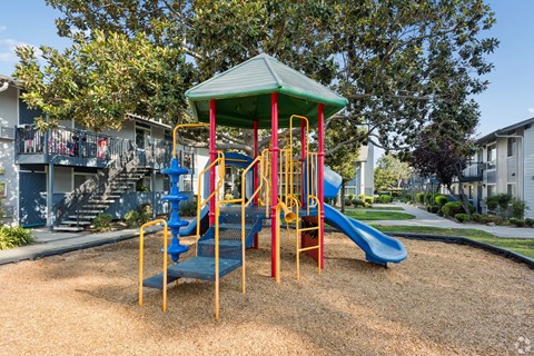 A playground with a blue slide and a green roof.