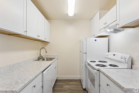A kitchen with white cabinets and a white stove top oven.