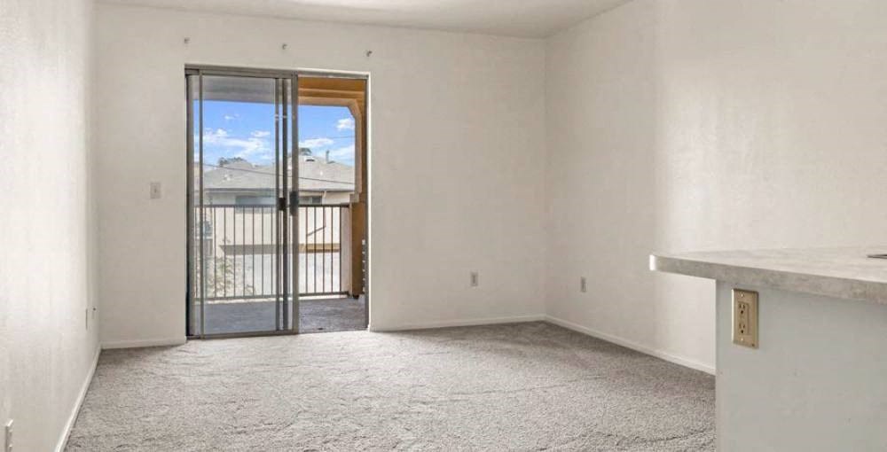 an empty room with a sliding glass door and a balcony