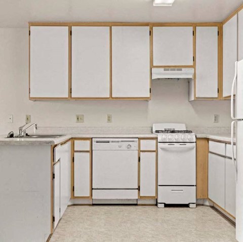 an empty kitchen with white appliances and white cabinets