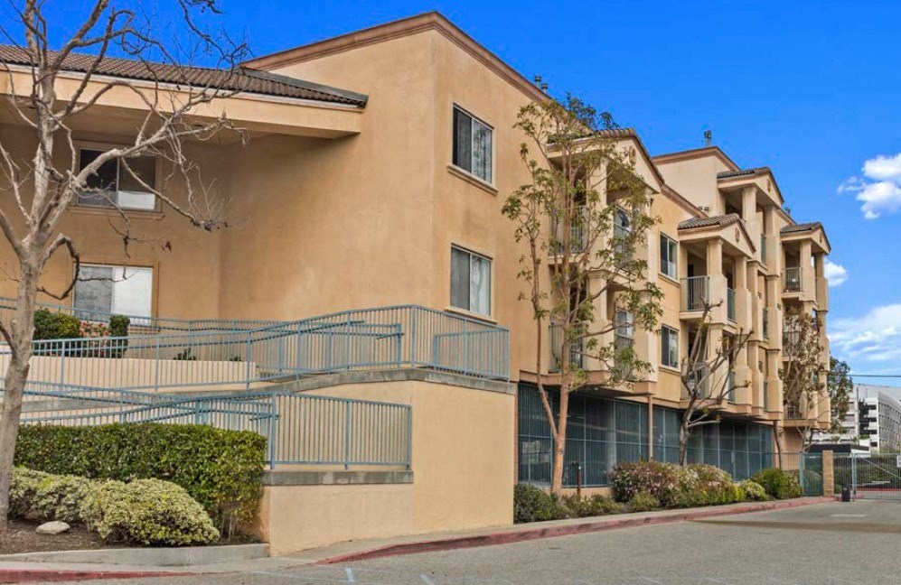 an apartment building with a staircase and trees in front of it